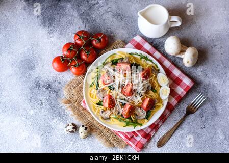 Spaghetti con funghi, formaggio, spinaci, rukkola e pomodori ciliegini. Piatti italiani, cultura mediterranea Foto Stock