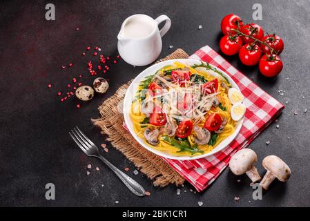 Spaghetti con funghi, formaggio, spinaci, rukkola e pomodori ciliegini. Piatti italiani, cultura mediterranea Foto Stock