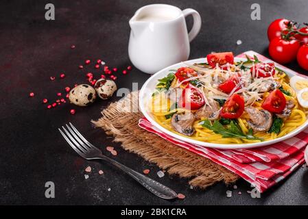 Spaghetti con funghi, formaggio, spinaci, rukkola e pomodori ciliegini. Piatti italiani, cultura mediterranea Foto Stock