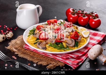 Spaghetti con funghi, formaggio, spinaci, rukkola e pomodori ciliegini. Piatti italiani, cultura mediterranea Foto Stock