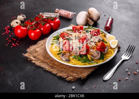 Spaghetti con funghi, formaggio, spinaci, rukkola e pomodori ciliegini. Piatti italiani, cultura mediterranea Foto Stock