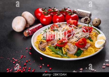 Spaghetti con funghi, formaggio, spinaci, rukkola e pomodori ciliegini. Piatti italiani, cultura mediterranea Foto Stock