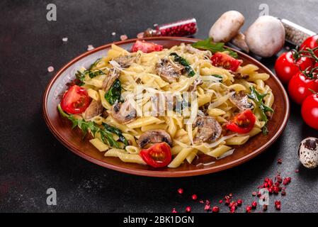 Pasta con funghi, formaggio, spinaci, rukkola e pomodori ciliegini. Piatti italiani, cultura mediterranea Foto Stock
