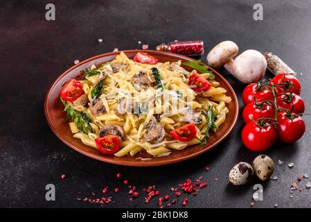 Pasta con funghi, formaggio, spinaci, rukkola e pomodori ciliegini. Piatti italiani, cultura mediterranea Foto Stock
