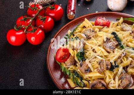 Pasta con funghi, formaggio, spinaci, rukkola e pomodori ciliegini. Piatti italiani, cultura mediterranea Foto Stock