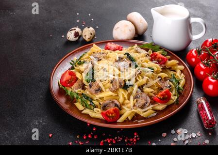 Pasta con funghi, formaggio, spinaci, rukkola e pomodori ciliegini. Piatti italiani, cultura mediterranea Foto Stock