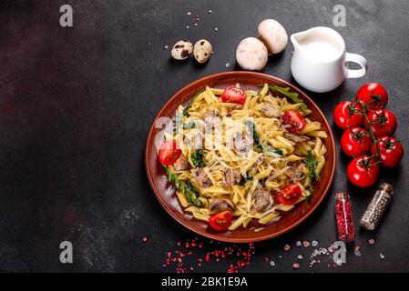Pasta con funghi, formaggio, spinaci, rukkola e pomodori ciliegini. Piatti italiani, cultura mediterranea Foto Stock