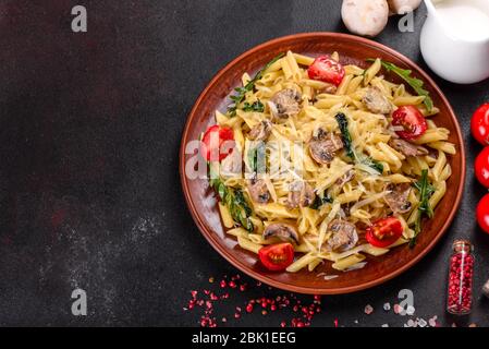 Pasta con funghi, formaggio, spinaci, rukkola e pomodori ciliegini. Piatti italiani, cultura mediterranea Foto Stock