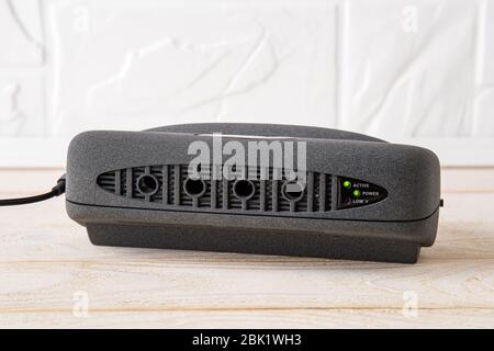 Ionizzatore d'aria nero su un tavolo di legno bianco. Purificatore d'aria con generatore anionico per l'aria fresca e la rimozione di polvere, odori sgradevoli in appartamento o in ufficio. Foto Stock