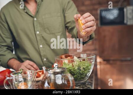 Uomo che spreme il succo di agrumi in una ciotola da portata Foto Stock