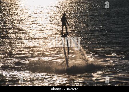 Volare a bordo di filatura sport acquatici estremi a Ras al Khaimah, Emirati Arabi Uniti vicino Dubai al tramonto silhouette divertirsi sull'acqua. Ricreazione Foto Stock