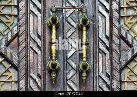Porta d'ingresso vintage in legno con grandi maniglie intagliate. Foto Stock