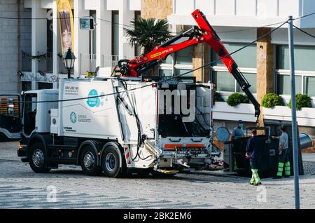 Garbage Collector carico rifiuti sulla strada indossando maschere facciali durante l'epidemia di Coronavirus Foto Stock