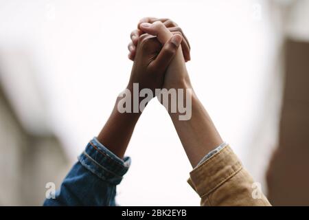 Simbolo di unità. Due attiviste donne in mano. Dimostranti che protestano insieme tenendo le mani. Foto Stock