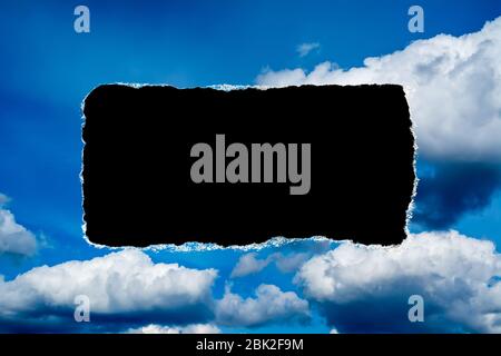 Un buco nel cielo di giorno con i bordi strappati, come sulla carta, con uno sfondo nero copyspace isolato al centro. Il concetto di cambiamento climatico globale in avanti Foto Stock