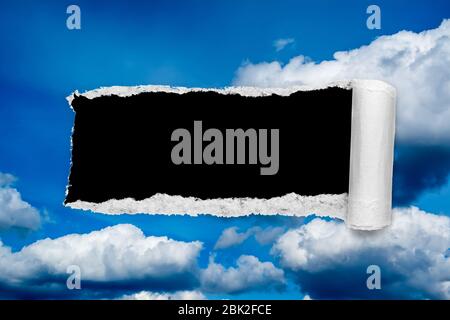 Un buco nel cielo di giorno con i bordi strappati, come sulla carta, con uno sfondo nero copyspace isolato al centro. Il concetto di cambiamento climatico globale in avanti Foto Stock