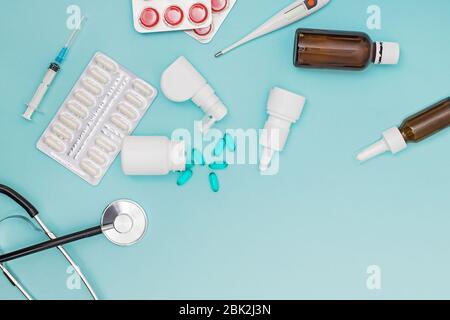 Vari farmaci, un termometro, spruzzi da un naso chiuso e un dolore in gola su uno sfondo blu. Foto Stock