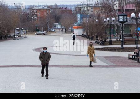 Tre persone solitarie che camminano sulla grande piazza della città Foto Stock