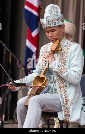 Ritratto di un uomo in abbigliamento tradizionale che gioca un kobyz su un palco al Kazakhstan Spring Festival presso Victoria Embankment Gardens, Londra Foto Stock
