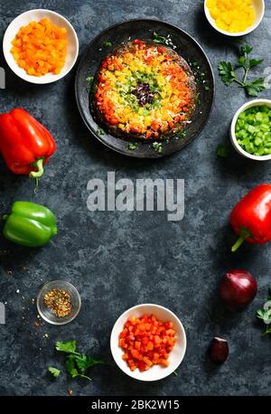 Cornice di arcobaleno veggie campana peperoni pizza crosta e ingredienti su sfondo di pietra blu. Vegetariano vegano o salutare concetto di cibo. Vista dall'alto, appartamento la Foto Stock