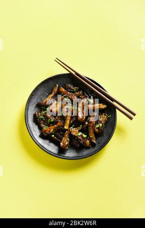 Stir-fry Bulgogi Eggplant su piastra su sfondo giallo con spazio di testo libero. Melanzane fritte in stile coreano. Foto Stock