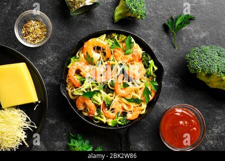 Gamberi e broccoli su fondo di pietra scura. Gustoso piatto sano per cena. Vista dall'alto, disposizione piatta Foto Stock