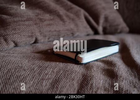 Notebook in pelle nera si trova sul divano, in luce naturale. Foto Stock