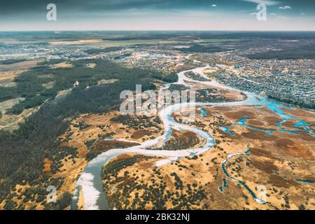 Bielorussia, Europa. Vista aerea Fiume curvo e piccola città nel paesaggio di inizio primavera. Curve del fiume e paesaggio erboso secco. Vista dall'alto di Beautiful Foto Stock