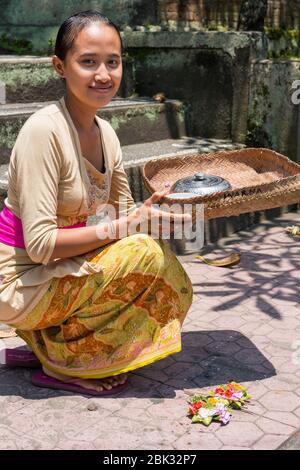 Giovane donna balinese offre le sue offerte quotidiane, canang sari, agli dei, Ubud, Bali, Indonesia Foto Stock