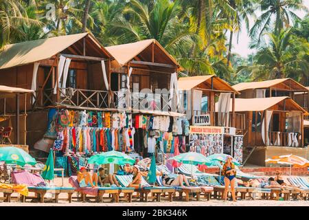 Canacona, Goa, India - 16 febbraio 2020: Persone che riposano alla famosa spiaggia di Palolem sullo sfondo negozio di abbigliamento da spiaggia in estate Sunny Day. Foto Stock