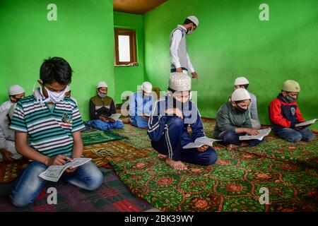 Srinagar, India. 1 maggio 2020. I bambini Kashmiri indossano maschere facciali protettive mentre recitano versetti dal Corano in un orfanotrofio in mezzo alla chiusura durante il mese santo del Ramadan.Musulmani in tutto il mondo stanno segnando il mese del Ramadan e hanno trovato modi diversi per celebrare il Ramadan quest'anno, come le restrizioni imposte dai paesi per frenare la diffusione del coronavirus hanno chiuso le moschee e vietato le riunioni. Ramadan è il mese più sacro del calendario islamico in cui i devoti digiunano dall'alba al tramonto. Credit: SOPA Images Limited/Alamy Live News Foto Stock