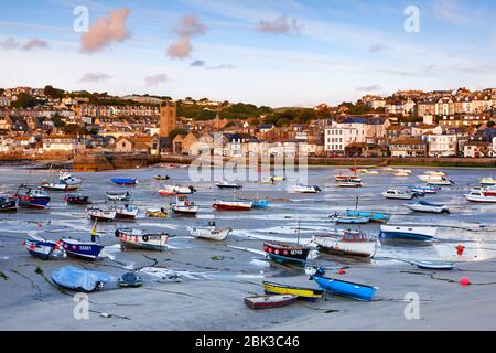 Low tide at St Ives Harbour as the early morning sunlight casts a warm glow over the waterfront Foto Stock