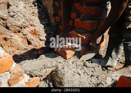 Mani di un uomo da vicino, che sta costruendo un muro di mattoni in Uganda, Africa Foto Stock