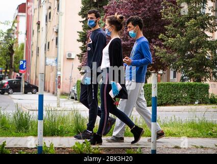 Belgrado, Serbia. 30 Aprile 2020. Due ragazzi e due donne camminano attraverso la città con maschere e guanti dopo la riapertura di parrucchieri, palestre, mercati e parchi durante la malattia di coronavirus (COVID-19). Il presidente Aleksandar Vucic aveva dichiarato lo stato di emergenza per fermare la diffusione del coronavirus. Anche il governo ha vietato a tutti i 65 anni di lasciare le loro case. A seguito del calo del numero di pazienti coronavirus il governo di questa settimana permette la riapertura di parrucchieri, palestre, mercati e parchi.Credit: Nikola Krstic/Alamy Live News Foto Stock