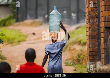 Donna che trasporta l'acqua a Entebbe, Uganda Foto Stock