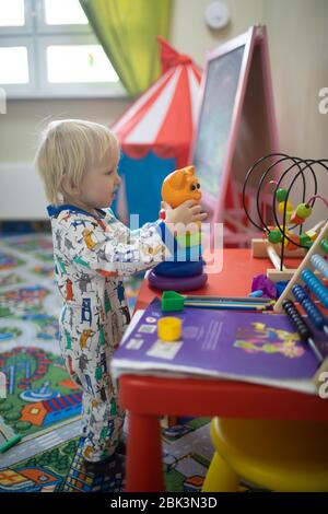 Ragazzo biondo che gioca con i giocattoli nella sala giochi per bambini. Foto Stock