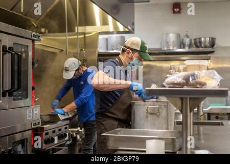 Detroit, Michigan, Stati Uniti. 1° maggio 2020. Gli operatori di cucina preparano i pasti per i senzatetto al Centro Papa Francesco. Il Centro, affiliato con SS. Pietro e Paolo Chiesa gesuita, ha dovuto chiudere i suoi spazi interni a causa della pandemia di coronavirus. Ora serve i pasti sulla strada e ha messo su docce e servizi igienici portatili, tende riscaldanti, e stazioni di lavaggio delle mani fuori. Credit: Jim West/Alamy Live News Foto Stock