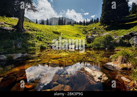La riflessione sulle montagne in chiaro del lago alla giornata di sole Foto Stock