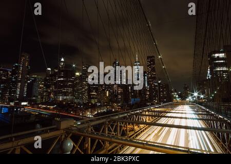 Foto a lunga esposizione di auto che passano di notte dal Ponte di Brooklyn - skyline di Manhattan sullo sfondo Foto Stock