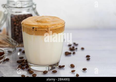 Il caffè Dalgona è una bevanda coreana fredda alla moda. Caffè gustoso e aromatico con latte e zucchero in un bicchiere su fondo bianco. Spazio di copia Foto Stock