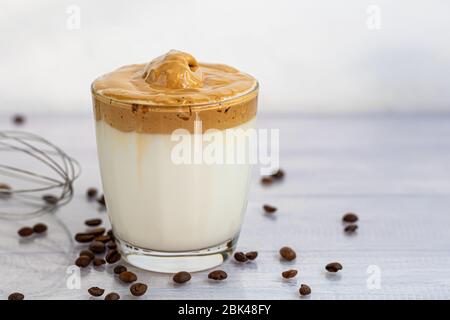 Il caffè Dalgona è una bevanda coreana fredda alla moda. Caffè gustoso e aromatico con latte e zucchero in un bicchiere su fondo bianco. Spazio di copia Foto Stock