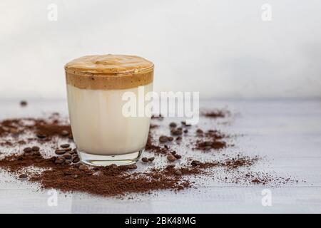 Il caffè Dalgona è una bevanda coreana fredda alla moda. Caffè gustoso e aromatico con latte e zucchero in un bicchiere su fondo bianco. Spazio di copia Foto Stock