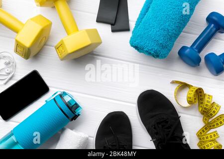 Flat lay top view attrezzature sportive, sneakers e smartphone su sfondo bianco in legno Foto Stock