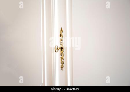 Porte bianche per armadio con chiave dorata in toppa, porte d'epoca di lusso in legno da primo piano Foto Stock