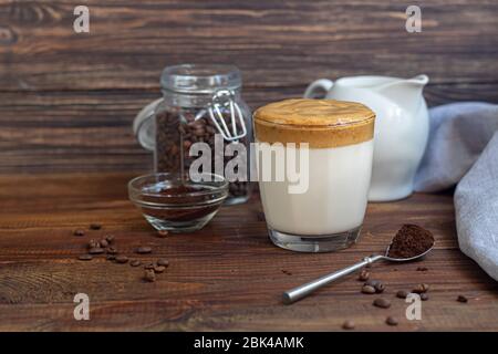 Il caffè Dalgona è una bevanda coreana fredda alla moda. Caffè gustoso e aromatico con latte e zucchero in un bicchiere su fondo di legno. Spazio di copia Foto Stock