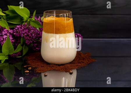 Il caffè Dalgona è una bevanda coreana fredda alla moda. Caffè gustoso e aromatico con latte e zucchero in un bicchiere su fondo nero. Spazio di copia Foto Stock