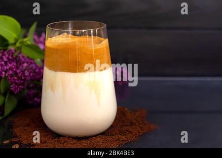 Il caffè Dalgona è una bevanda coreana fredda alla moda. Caffè gustoso e aromatico con latte e zucchero in un bicchiere su fondo nero. Spazio di copia Foto Stock