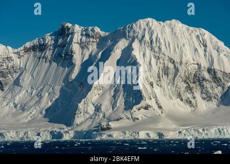 Vista sulle montagne al sole nello stretto di Gerlache vicino all'isola di Cuverville nella regione della penisola antartica Foto Stock