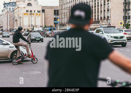 Mosca, Russia - 7 LUGLIO 2017: Il giovane uomo in bicicletta attraversa una strada trafficata piena di automobili Foto Stock