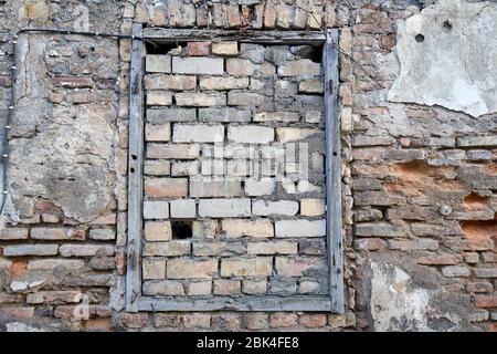 La finestra è coperta di mattoni in vecchio muro di mattoni Foto Stock